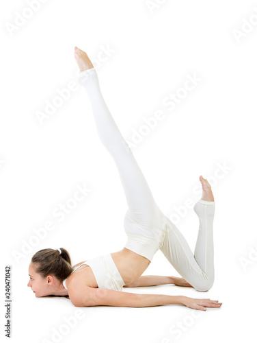 A young woman in a white suit performs acrobatic elements and yoga.