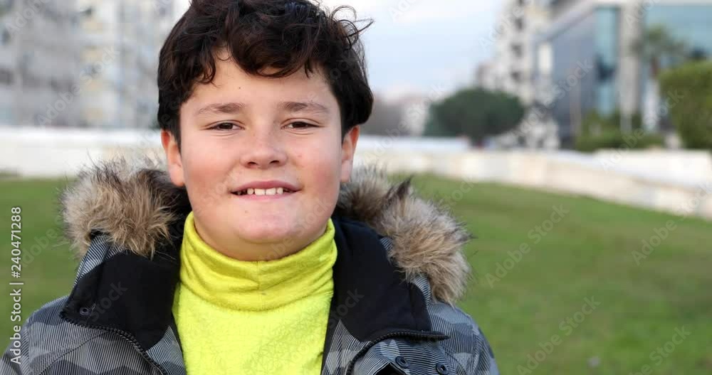 Happy schoolchild with winter clothes looking at the camera smiling and posing in the city park Happy schoolchild with winter clothes looking at the camera smiling and posing in the city park