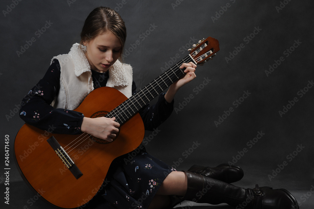 Fototapeta premium Girl with guitar. Studio light. Dark background.