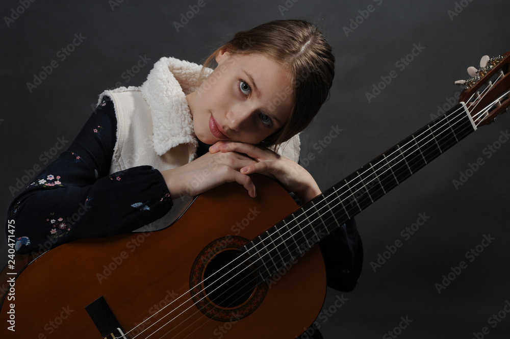 Fototapeta premium Girl with guitar. Studio light. Dark background.