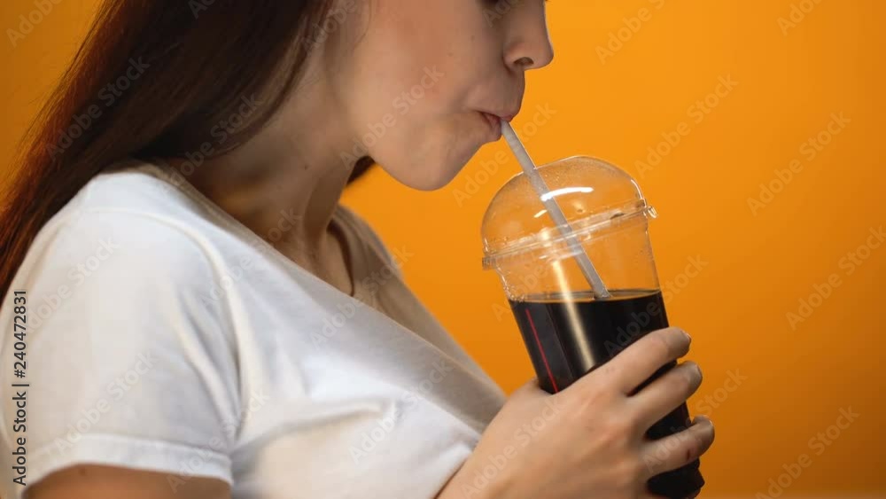 Young woman drinking soda and smiling, sugar addiction, high calorie beverages Young woman drinking soda and smiling, sugar addiction, high calorie beverages