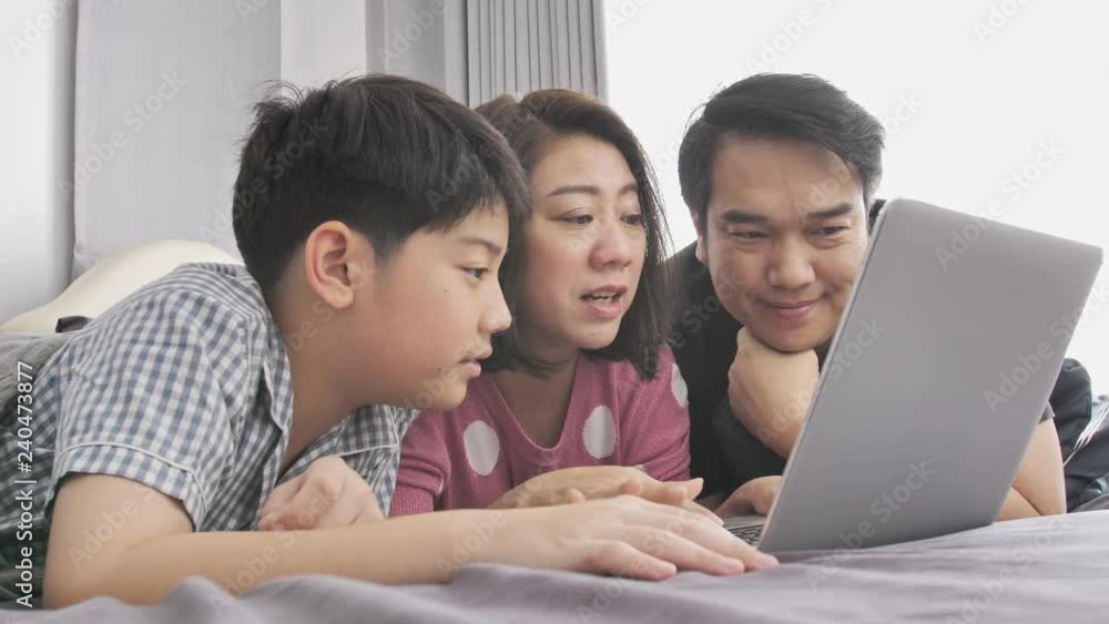 Happy family Father mother and son watching on laptop computer and having fun, Slow motion 4K asian family rest on bed with laptop computer Happy family Father mother and son watching on laptop computer and having fun, Slow motion 4K asian family rest on bed with laptop computer