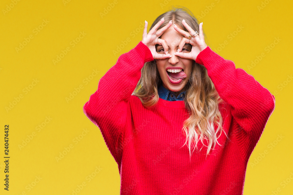 Beautiful young blonde woman wearing winter sweater over isolated background doing ok gesture like binoculars sticking tongue out, eyes looking through fingers. Crazy expression. Beautiful young blonde woman wearing winter sweater over isolated background doing ok gesture like binoculars sticking tongue out, eyes looking through fingers. Crazy expression.