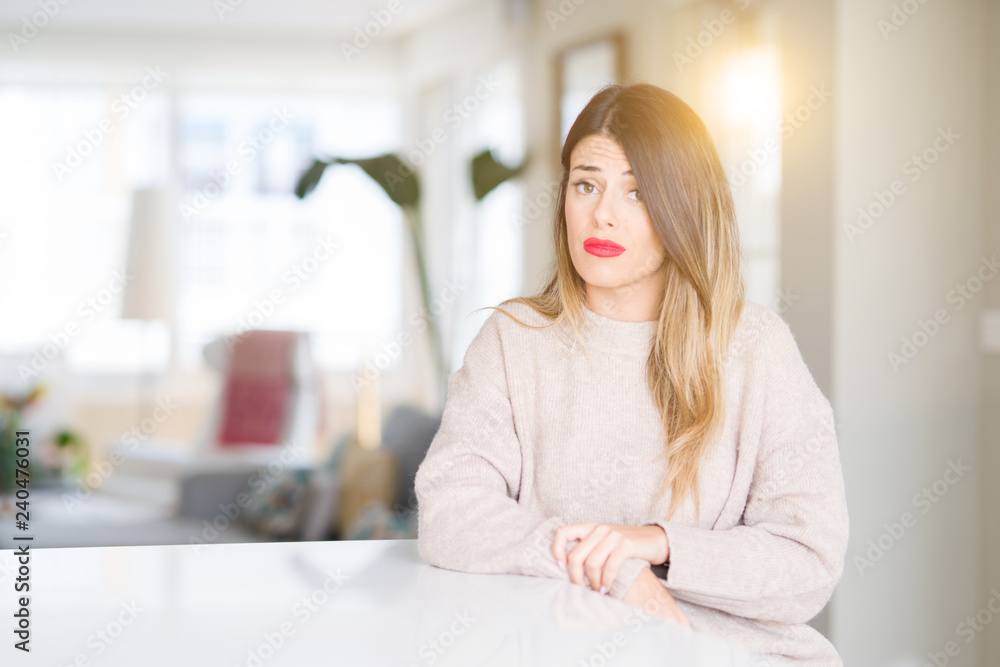 Young beautiful woman wearing winter sweater at home skeptic and nervous, frowning upset because of problem. Negative person. Young beautiful woman wearing winter sweater at home skeptic and nervous, frowning upset because of problem. Negative person.