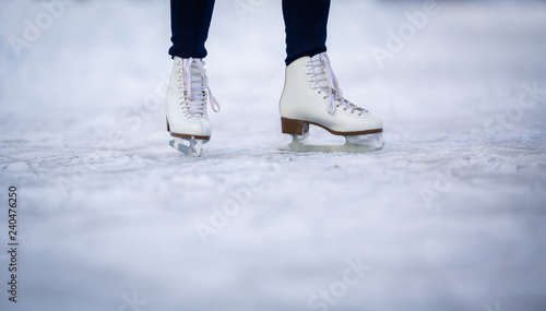 Young woman ice skating outdoors on a pond on a freezing winter day - detail of the skates