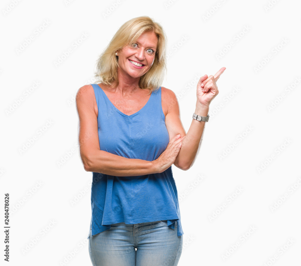 Middle age blonde woman over isolated background with a big smile on face, pointing with hand and finger to the side looking at the camera. Middle age blonde woman over isolated background with a big smile on face, pointing with hand and finger to the side looking at the camera.