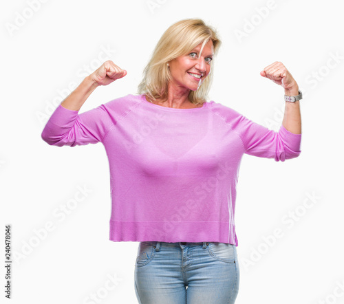 Middle age blonde woman over isolated background showing arms muscles smiling proud. Fitness concept.