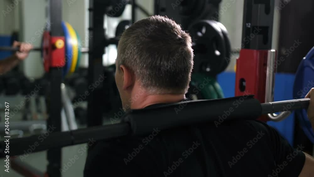 View from the back. Man crouches with a barbell 4K Slow Mo View from the back. Man crouches with a barbell 4K Slow Mo