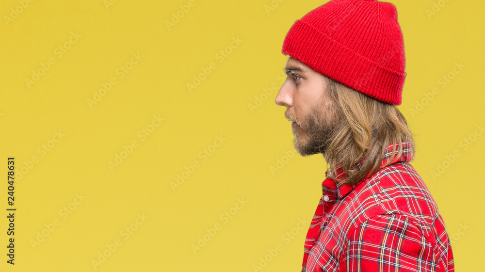 Young handsome man with long hair wearing red cap over isolated background looking to side, relax profile pose with natural face with confident smile. Young handsome man with long hair wearing red cap over isolated background looking to side, relax profile pose with natural face with confident smile.