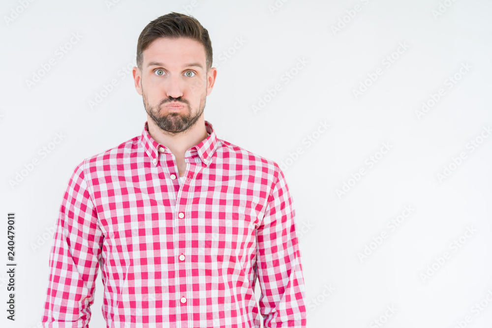 Fototapeta premium Young handsome man wearing shirt over isolated background puffing cheeks with funny face. Mouth inflated with air, crazy expression.