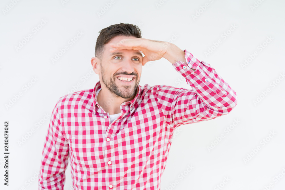 Young handsome man wearing shirt over isolated background very happy and smiling looking far away with hand over head. Searching concept. Young handsome man wearing shirt over isolated background very happy and smiling looking far away with hand over head. Searching concept.