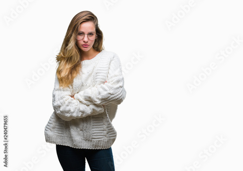 Young beautiful blonde woman wearing winter sweater and sunglasses over isolated background skeptic and nervous, disapproving expression on face with crossed arms. Negative person. photo