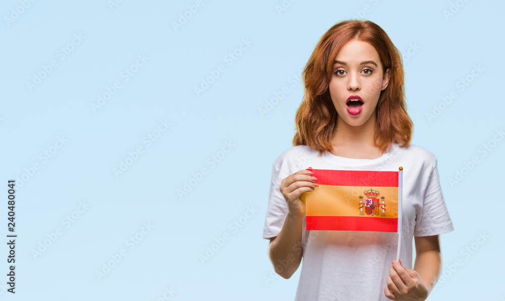 Young beautiful woman holding flag of spain over isolated background scared in shock with a surprise face, afraid and excited with fear expression Young beautiful woman holding flag of spain over isolated background scared in shock with a surprise face, afraid and excited with fear expression