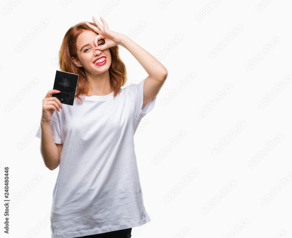 Young beautiful woman holding passport of australia over isolated background with happy face smiling doing ok sign with hand on eye looking through fingers Young beautiful woman holding passport of australia over isolated background with happy face smiling doing ok sign with hand on eye looking through fingers