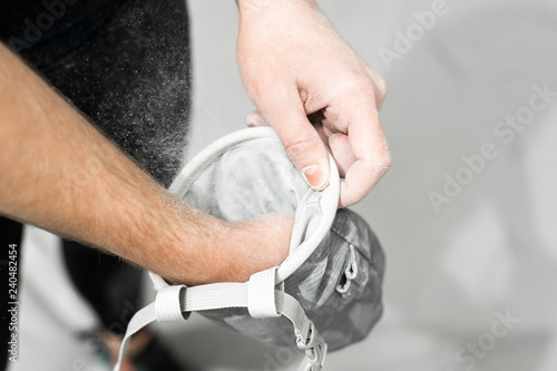 Rock climber processes hands with sports magnesia in a special bag