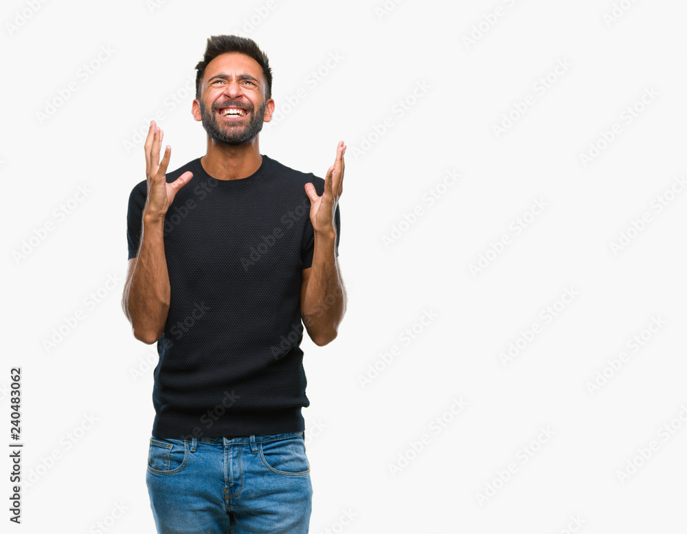 Fototapeta premium Adult hispanic man over isolated background crazy and mad shouting and yelling with aggressive expression and arms raised. Frustration concept.