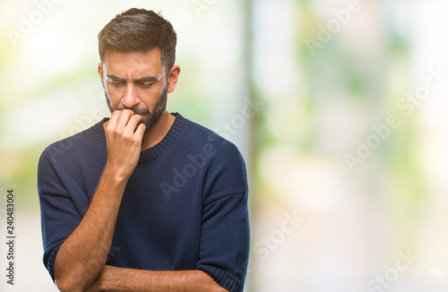 Adult hispanic man over isolated background looking stressed and nervous with hands on mouth biting nails. Anxiety problem. photo