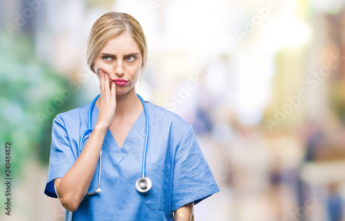 Young beautiful blonde doctor surgeon nurse woman over isolated background thinking looking tired and bored with depression problems with crossed arms.