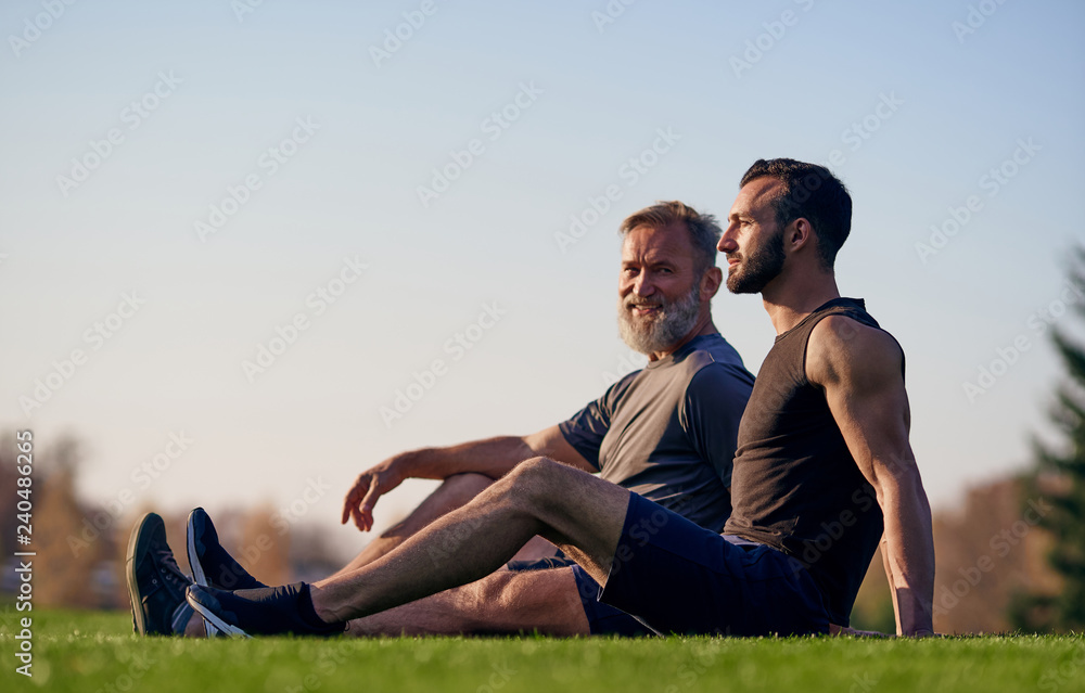 The old and young sportsmen sitting on the grass