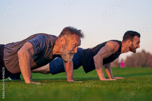 The young and old men push up together on the grass