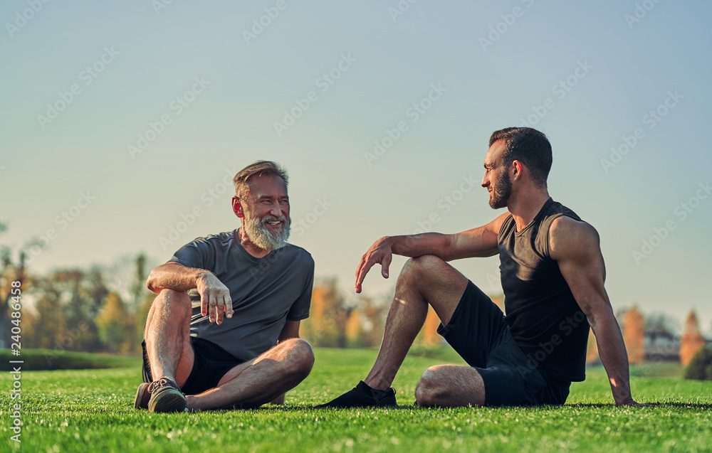 The old and young sportsmen sitting on the grass The old and young sportsmen sitting on the grass
