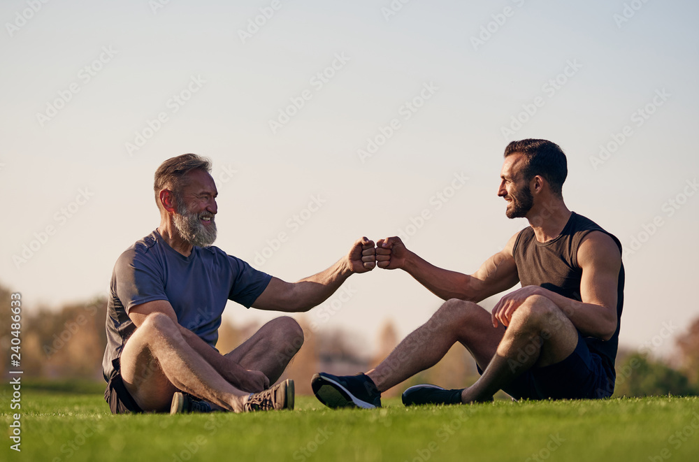 The two men sitting on the grass and greeting