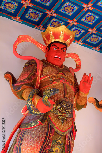Heavenly Kings holding snake statue in Dajue Temple, China photo