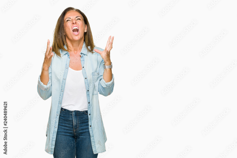 Obraz premium Middle age adult woman wearing casual denim shirt over isolated background crazy and mad shouting and yelling with aggressive expression and arms raised. Frustration concept.