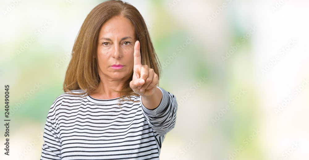 Beautiful middle age woman wearing stripes sweater over isolated background Pointing with finger up and angry expression Beautiful middle age woman wearing stripes sweater over isolated background Pointing with finger up and angry expression