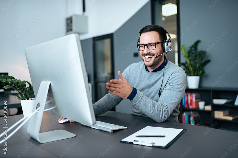 Smiling call center agent talking on the phone and looking a monitor. Smiling call center agent talking on the phone and looking a monitor.