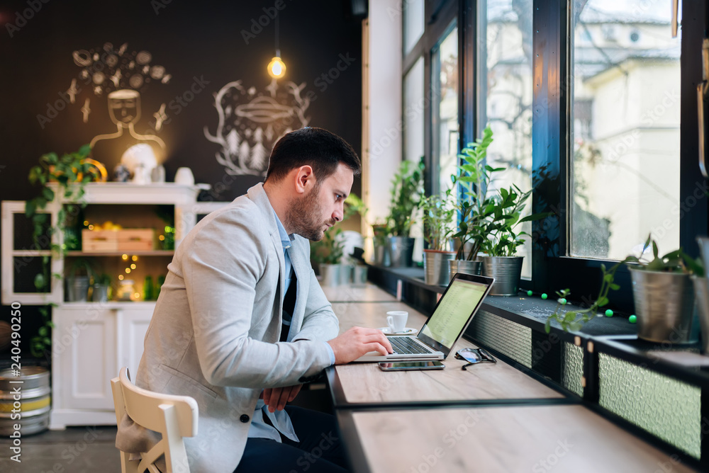 Side view of a serious entrepreneur looking at laptop screen at the cafe Side view of a serious entrepreneur looking at laptop screen at the cafe