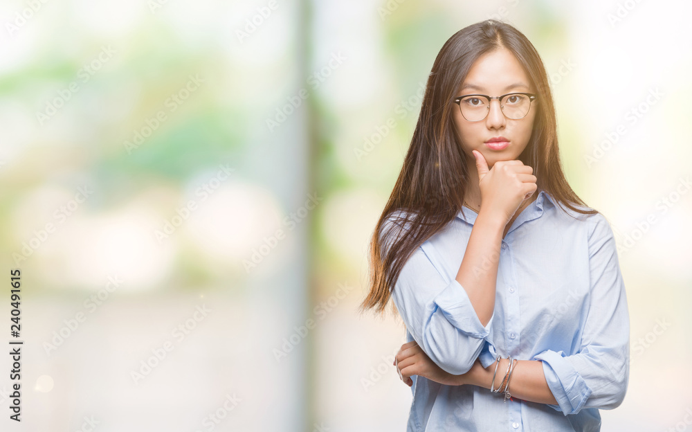 Young asian business woman wearing glasses over isolated background looking confident at the camera with smile with crossed arms and hand raised on chin. Thinking positive. Young asian business woman wearing glasses over isolated background looking confident at the camera with smile with crossed arms and hand raised on chin. Thinking positive.