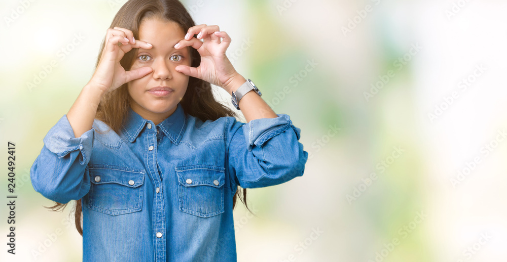 Young beautiful brunette woman wearing blue denim shirt over isolated background Trying to open eyes with fingers, sleepy and tired for morning fatigue Young beautiful brunette woman wearing blue denim shirt over isolated background Trying to open eyes with fingers, sleepy and tired for morning fatigue