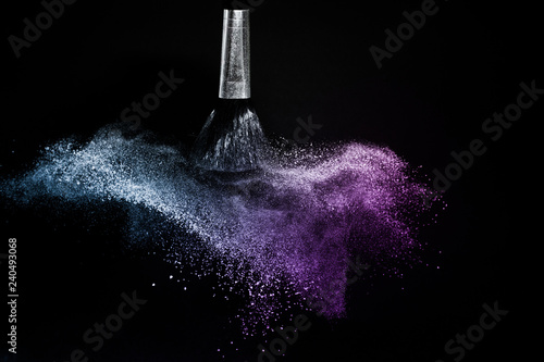 Cosmetic brush with purple and blue ocean cosmetic powder spreading for makeup artist or graphic design in black background, look like a lively and joyful mood.