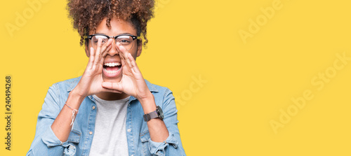 Beautiful young african american woman wearing glasses over isolated background Shouting angry out loud with hands over mouth