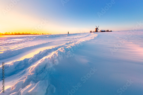 Wooden windmill on background winter sunrise. Dudutki village, Minsk Region, Belarus photo