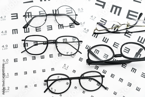 Eyeglasses and visual acuity chart in white background photo