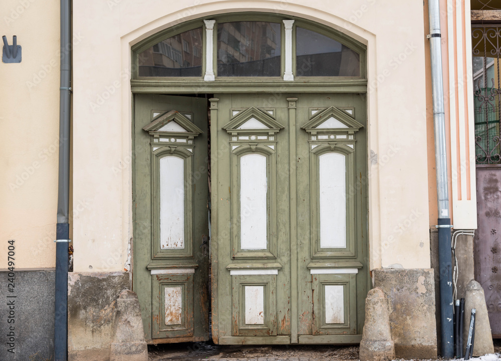 Opened , green hand carved wooden entrance on a residentual house . Opened , green hand carved wooden entrance on a residentual house .