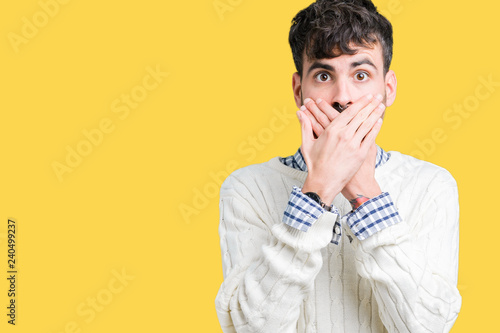 Young handsome man wearing winter sweater over isolated background shocked covering mouth with hands for mistake. Secret concept.