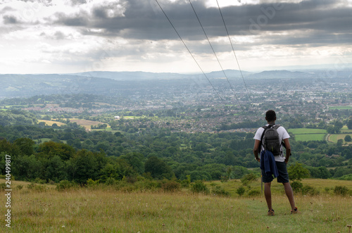Hiker on the Cotswold Way overlooking the town of Cheltenham, Gloucestershire, England