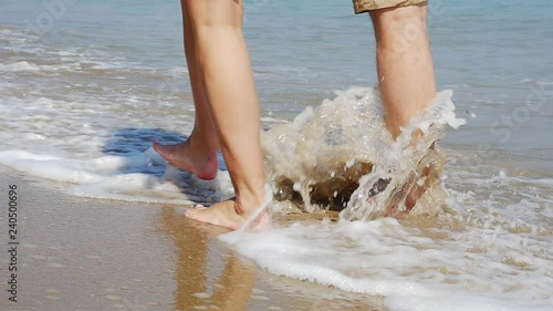 Close up of a young couple legs on romantic vacation walking on empty beach, slow motion