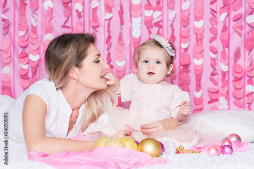 Portrait of mother with daughter in a festive pink interior