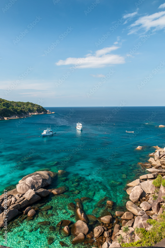 Boats moored in a clear tropical ocean next to a coral reef (Similan Islands)