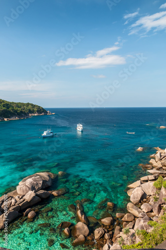 Boats moored in a clear tropical ocean next to a coral reef (Similan Islands)