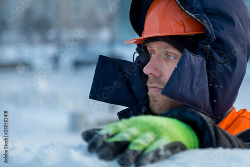 Portrait of an assembler in an orange helmet with a hood