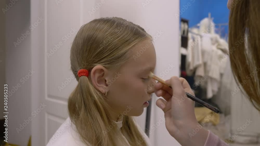 Visagiste applying eyehadow on eyelid of makeup model in makeup studio. Makeup artist doing make up face for young teenager girl in beauty salon. Beauty and fashion Visagiste applying eyehadow on eyelid of makeup model in makeup studio. Makeup artist doing make up face for young teenager girl in beauty salon. Beauty and fashion