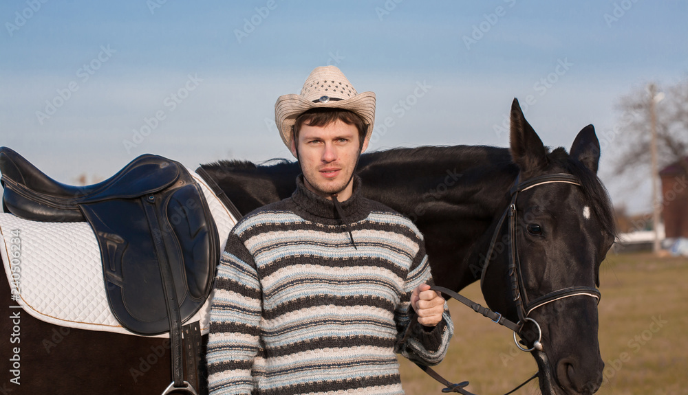 Man nearby horse, striped pullover, blue jeans, hat, close up Man nearby horse, striped pullover, blue jeans, hat, close up