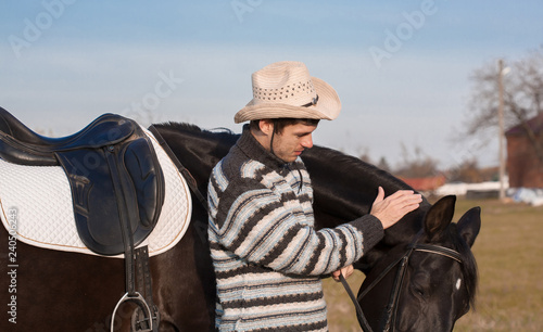  Man nearby horse, striped pullover, blue jeans, hat, close up