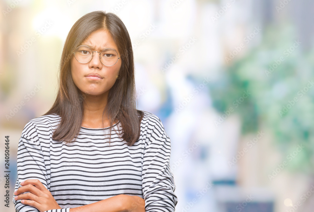 Young asian woman wearing glasses over isolated background skeptic and nervous, disapproving expression on face with crossed arms. Negative person. Young asian woman wearing glasses over isolated background skeptic and nervous, disapproving expression on face with crossed arms. Negative person.