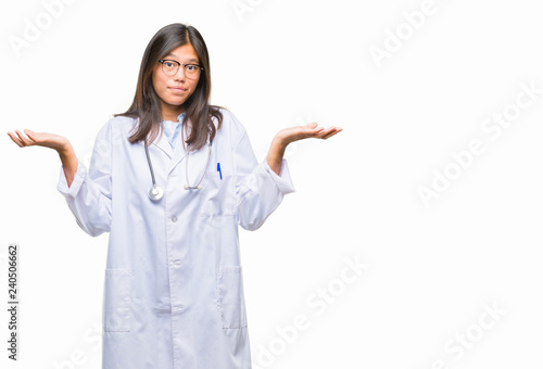 Young asian doctor woman over isolated background clueless and confused expression with arms and hands raised. Doubt concept.
